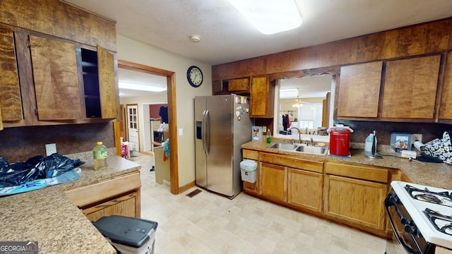 kitchen featuring white stove, sink, stainless steel refrigerator with ice dispenser, and light tile patterned floors