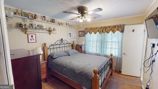 bedroom featuring a textured ceiling, ceiling fan, wood-type flooring, and ornamental molding