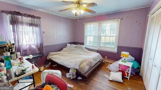 bedroom featuring ornamental molding, baseboard heating, ceiling fan, and hardwood / wood-style floors