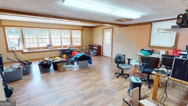 home office with beam ceiling, wood-type flooring, and a textured ceiling