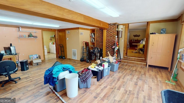 misc room featuring brick wall, washer / clothes dryer, hardwood / wood-style flooring, and beamed ceiling