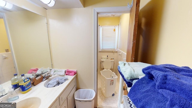 bathroom with vanity, toilet, and tile walls