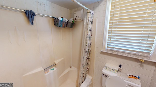 bathroom with tile walls, shower / bath combo with shower curtain, and toilet