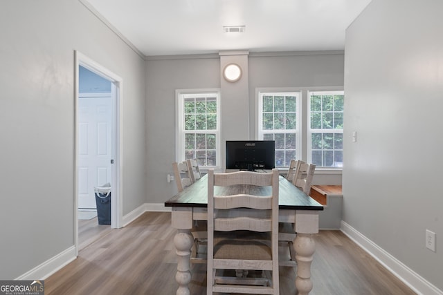 dining area with crown molding and light hardwood / wood-style flooring