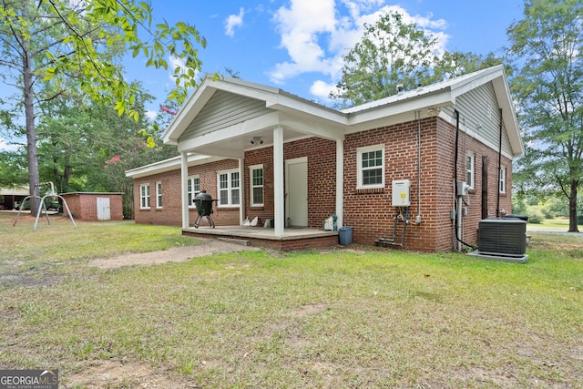 rear view of property featuring central air condition unit and a lawn