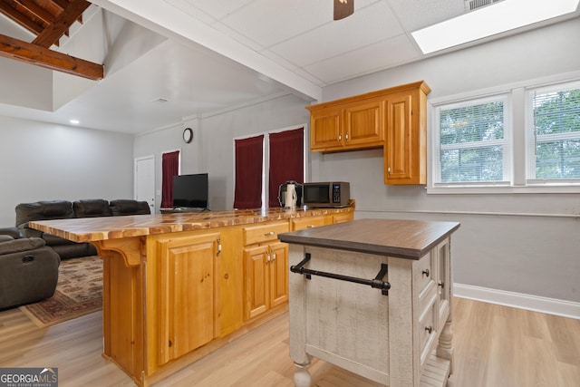 kitchen with light hardwood / wood-style flooring, a center island, beam ceiling, butcher block countertops, and ceiling fan