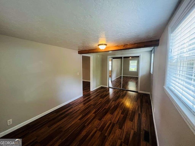 spare room featuring dark hardwood / wood-style flooring and a textured ceiling