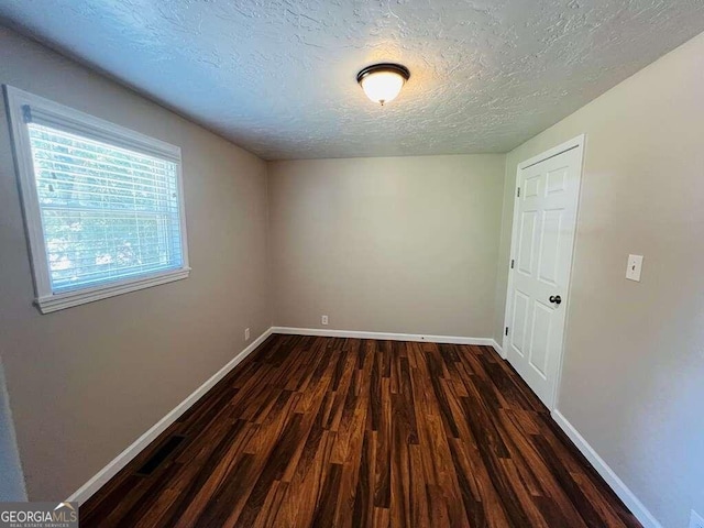 spare room with a textured ceiling and hardwood / wood-style floors