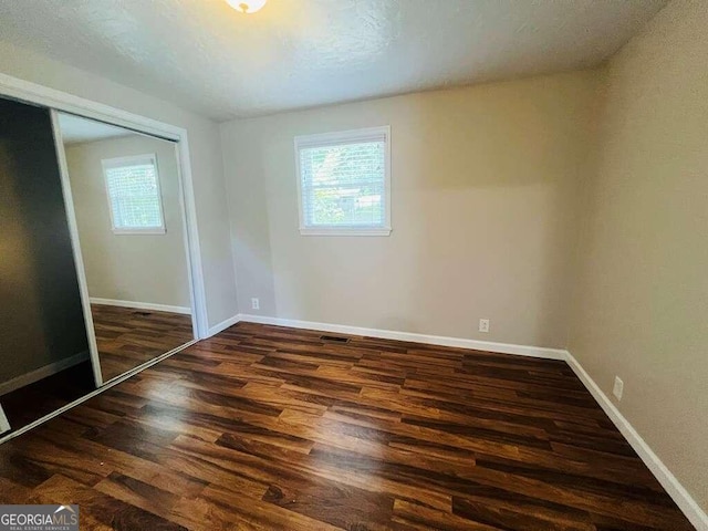 unfurnished bedroom featuring dark wood-type flooring and a closet