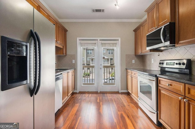 kitchen featuring backsplash, crown molding, dark wood-type flooring, and appliances with stainless steel finishes