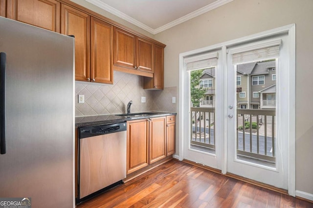 kitchen with decorative backsplash, appliances with stainless steel finishes, crown molding, sink, and dark hardwood / wood-style floors