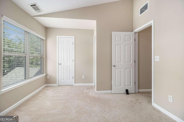 unfurnished bedroom with light colored carpet and vaulted ceiling