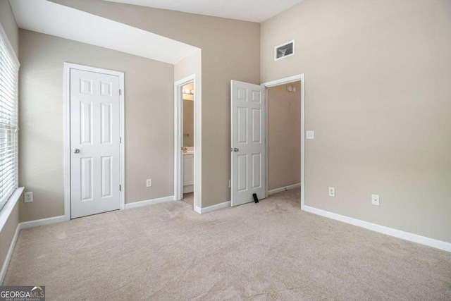 unfurnished bedroom with vaulted ceiling, light carpet, and multiple windows