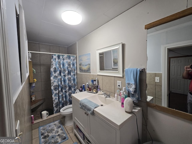 bathroom with curtained shower, tile patterned floors, toilet, vanity, and tile walls