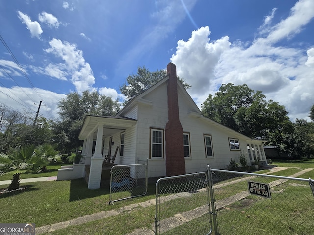 view of side of home featuring covered porch and a lawn