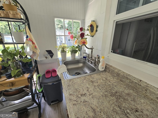 kitchen featuring light stone counters, sink, and wood walls