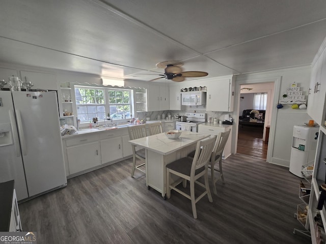 kitchen featuring white appliances, dark hardwood / wood-style floors, ceiling fan, a kitchen bar, and white cabinetry