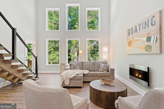 living room with light wood-type flooring and a towering ceiling