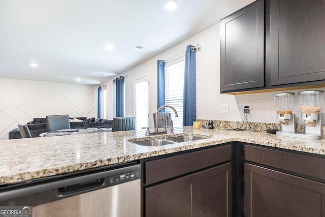 kitchen featuring kitchen peninsula, dishwasher, light stone countertops, dark brown cabinetry, and sink