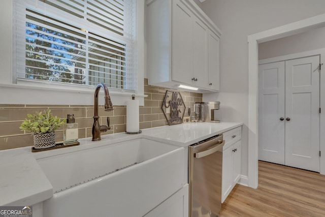 kitchen featuring tasteful backsplash, white cabinetry, sink, and stainless steel dishwasher