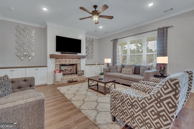 living room with ceiling fan, light hardwood / wood-style floors, crown molding, and a brick fireplace