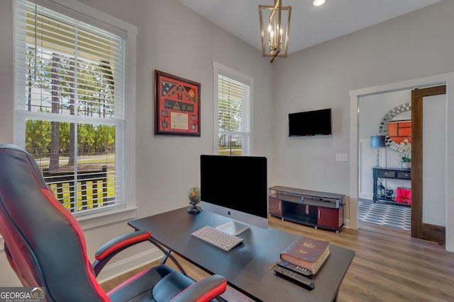 home office with hardwood / wood-style floors and a notable chandelier