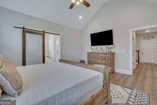 bedroom featuring high vaulted ceiling, ensuite bath, ceiling fan, a barn door, and light wood-type flooring