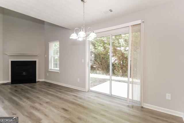 unfurnished living room featuring a chandelier, a healthy amount of sunlight, and hardwood / wood-style flooring