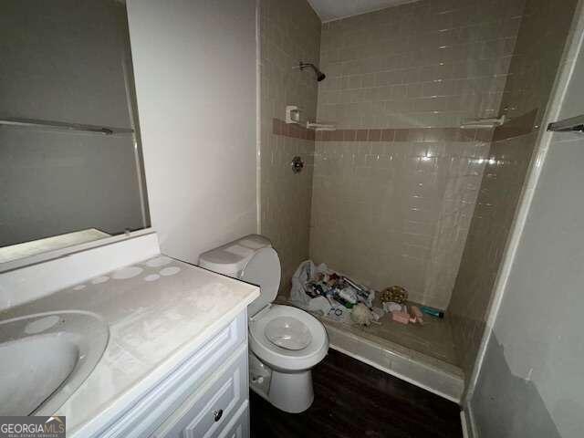 bathroom with vanity, tiled shower, toilet, and hardwood / wood-style flooring