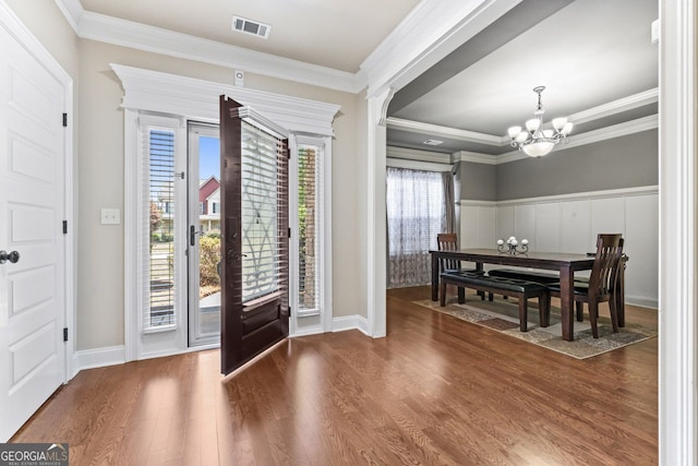 foyer with crown molding, a notable chandelier, and hardwood / wood-style flooring