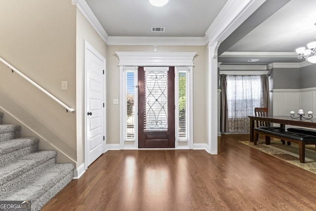 foyer featuring dark hardwood / wood-style flooring, ornamental molding, and a chandelier