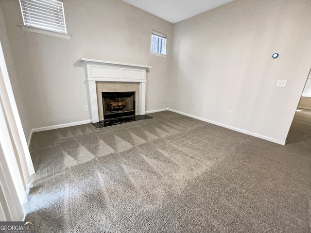 unfurnished living room featuring a high end fireplace and dark colored carpet