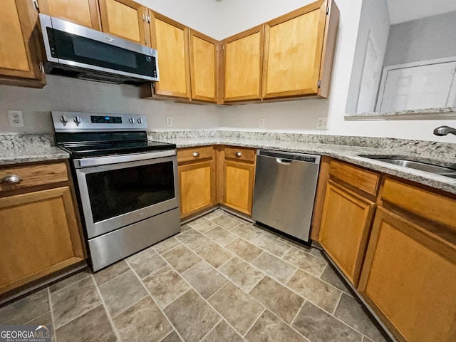 kitchen featuring light stone countertops, sink, and appliances with stainless steel finishes