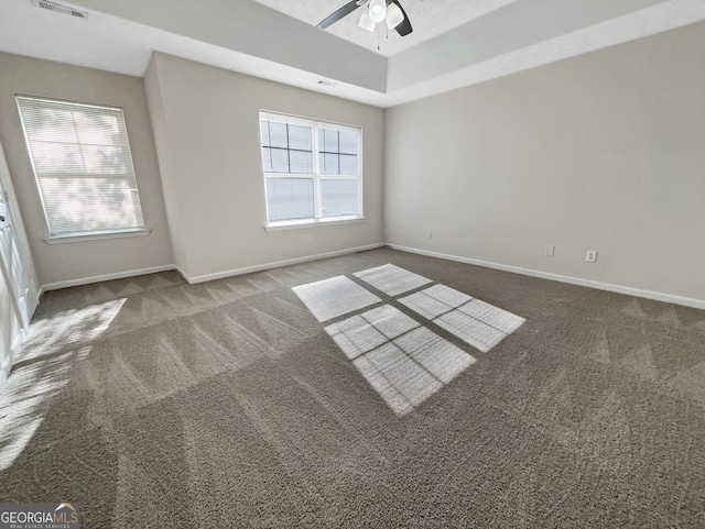 carpeted empty room featuring a tray ceiling and ceiling fan