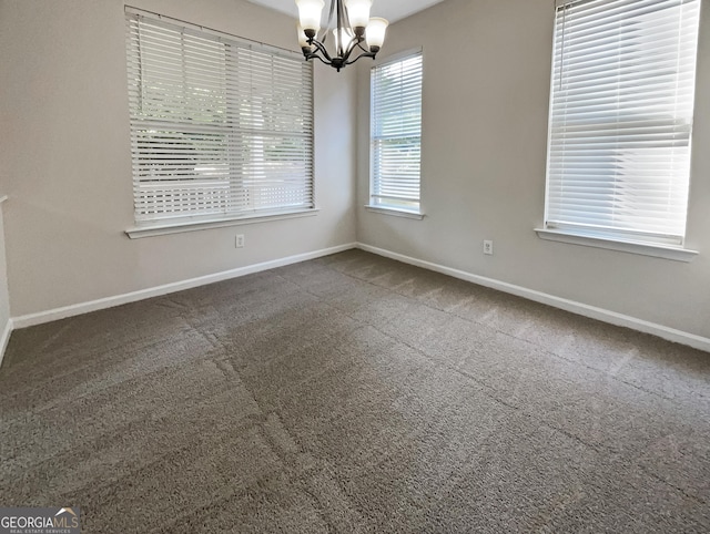 unfurnished room with a chandelier and dark colored carpet