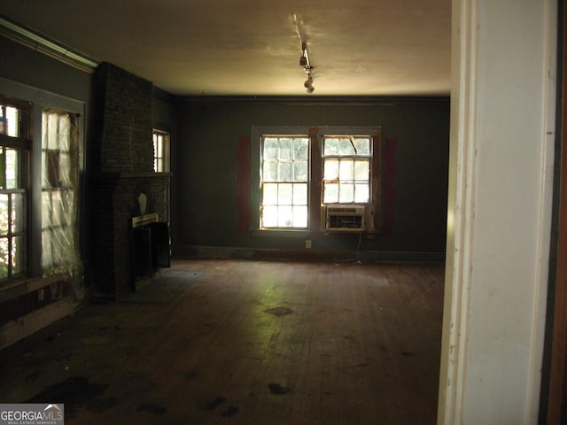 unfurnished dining area featuring dark hardwood / wood-style floors, a large fireplace, ornamental molding, and cooling unit