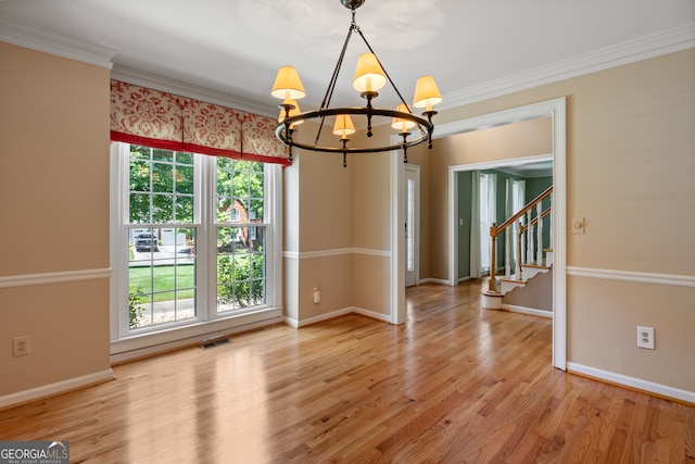 empty room featuring light hardwood / wood-style floors, a chandelier, and ornamental molding