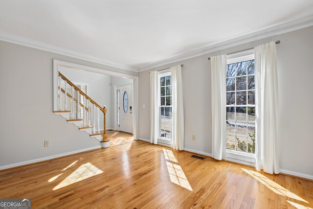 unfurnished room featuring light hardwood / wood-style floors, a large fireplace, ornamental molding, and french doors