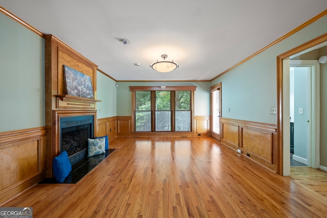 unfurnished living room with light hardwood / wood-style floors, a large fireplace, and ornamental molding