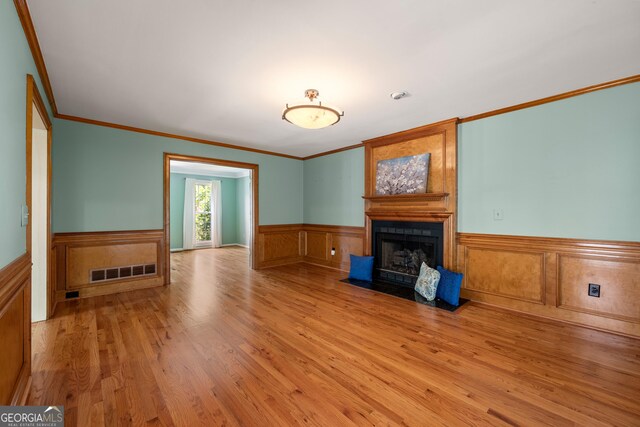 unfurnished living room featuring light wood-type flooring and ornamental molding