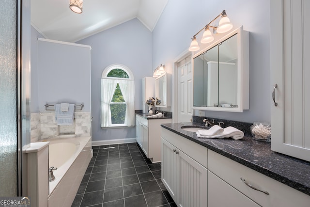 bathroom featuring a relaxing tiled tub, vaulted ceiling, vanity, and tile patterned floors