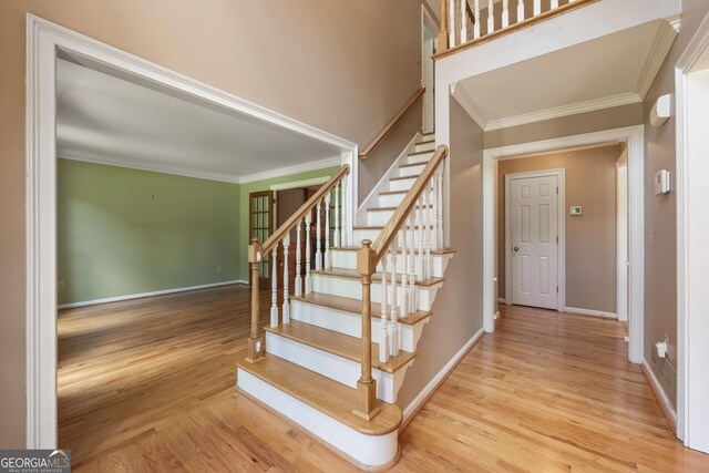 stairs with crown molding and wood-type flooring