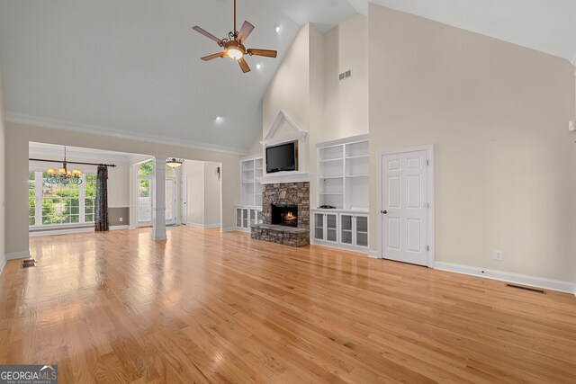 unfurnished living room with decorative columns, built in shelves, ceiling fan with notable chandelier, high vaulted ceiling, and a fireplace