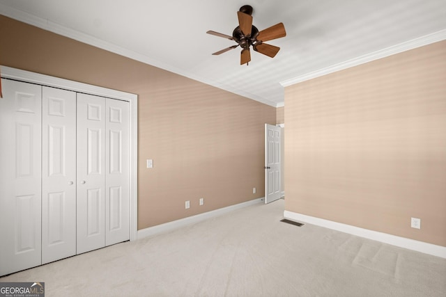 unfurnished bedroom featuring a closet, light colored carpet, ceiling fan, and ornamental molding