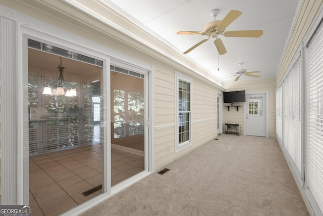 unfurnished sunroom with ceiling fan with notable chandelier