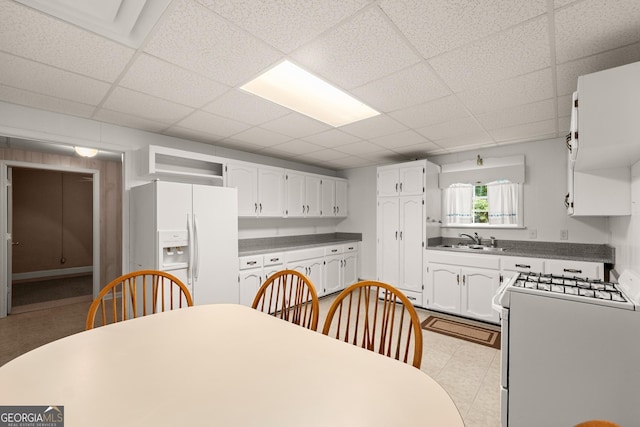 kitchen featuring white cabinetry, sink, white refrigerator with ice dispenser, stove, and a paneled ceiling