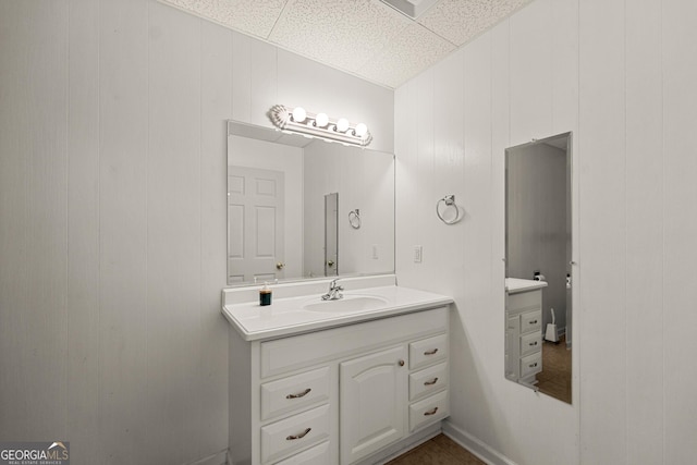 bathroom featuring vanity, a drop ceiling, and wooden walls