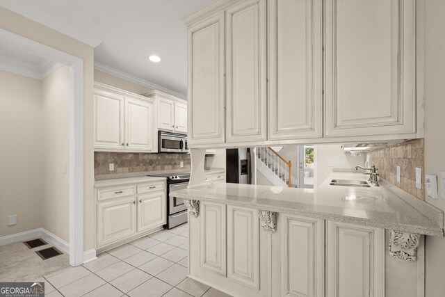 kitchen with white cabinetry, sink, kitchen peninsula, appliances with stainless steel finishes, and ornamental molding