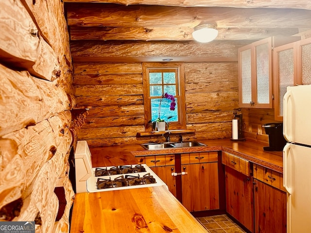 kitchen with white appliances, sink, and rustic walls