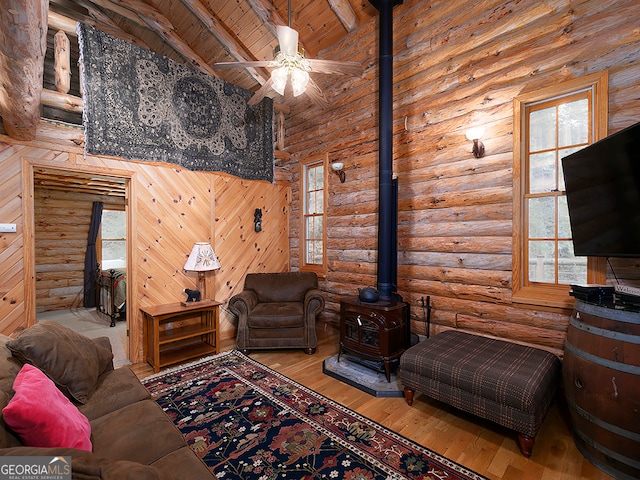 living room featuring hardwood / wood-style floors, ceiling fan, high vaulted ceiling, beamed ceiling, and log walls